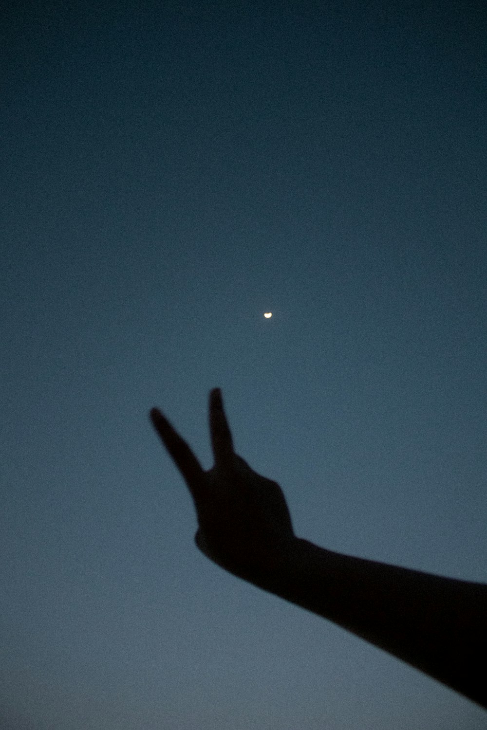 a person's hand reaching for the moon in the sky