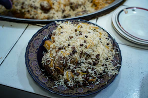 Close-up of a beautifully arranged platter of Kabuli Pulao with vibrant raisins and carrots.