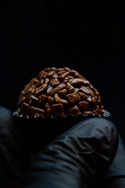 Hand holding a shiny chocolate bonbon with a delicate filling