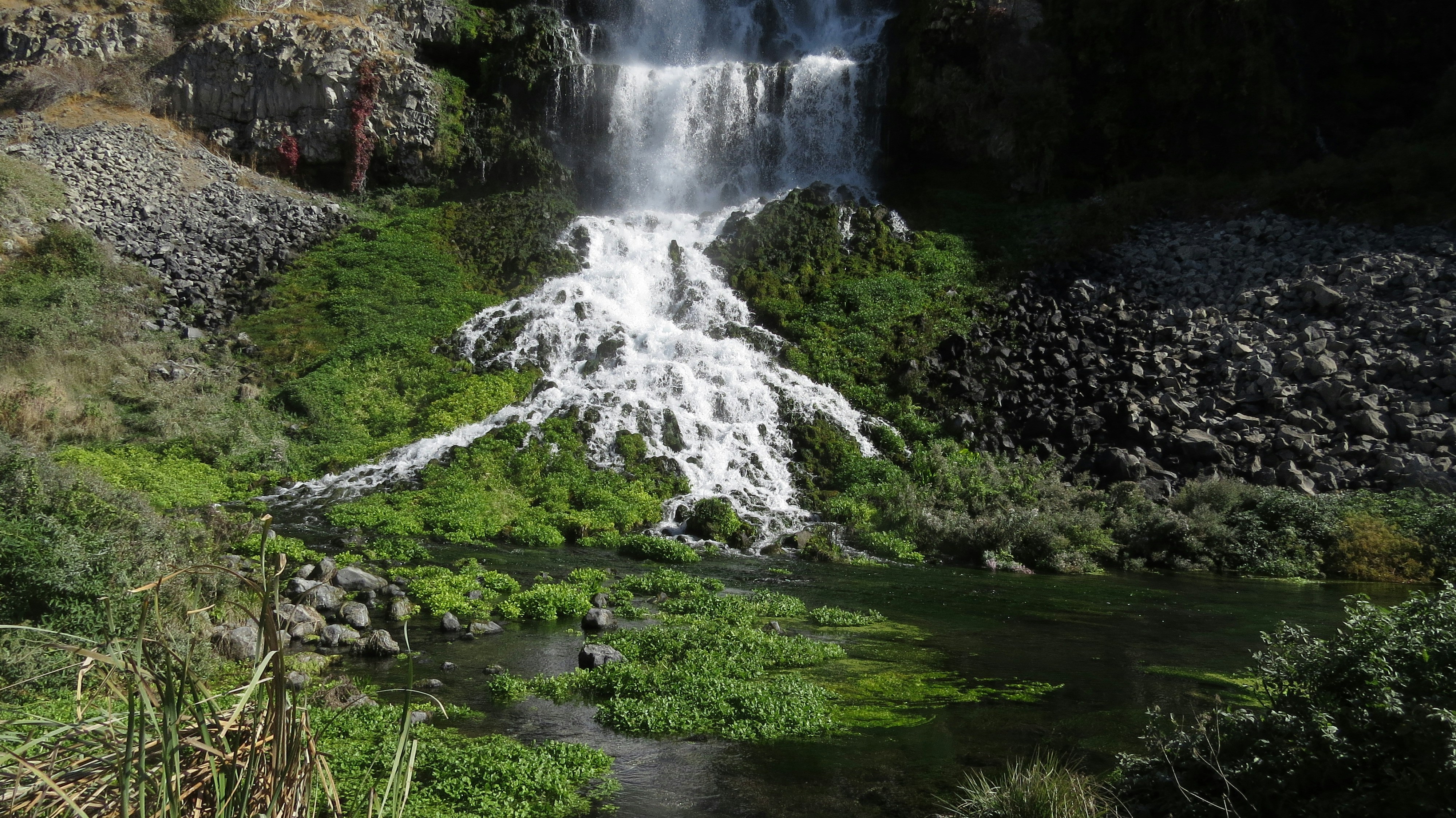 uma grande cachoeira com água em cascata ao seu lado