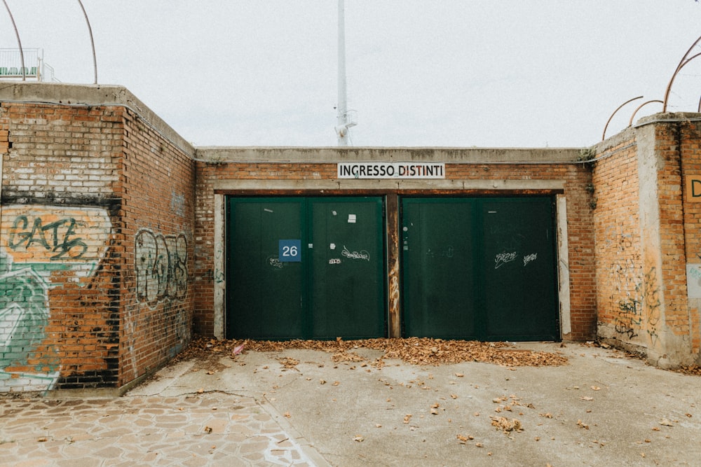 a couple of green doors sitting inside of a brick building