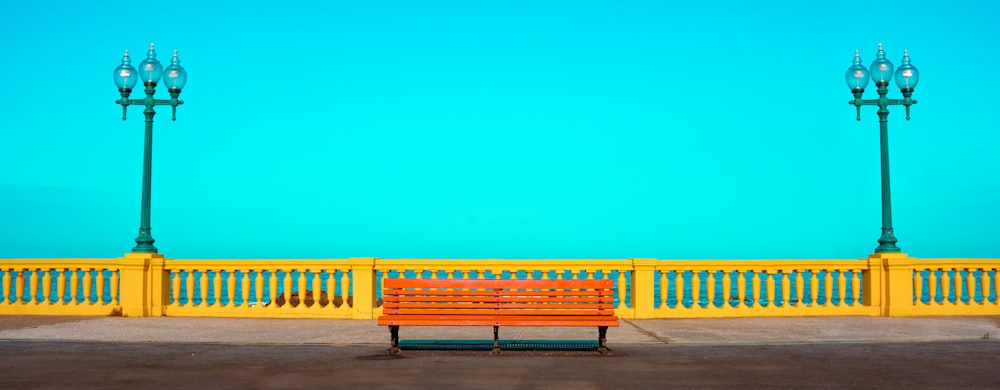 a red bench sitting in front of a yellow fence