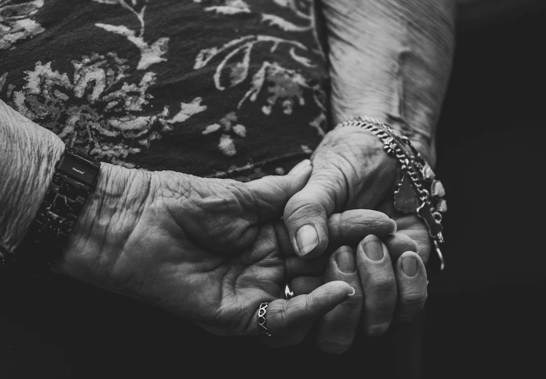 Une aidante tient tendrement la main de sa mère âgée
