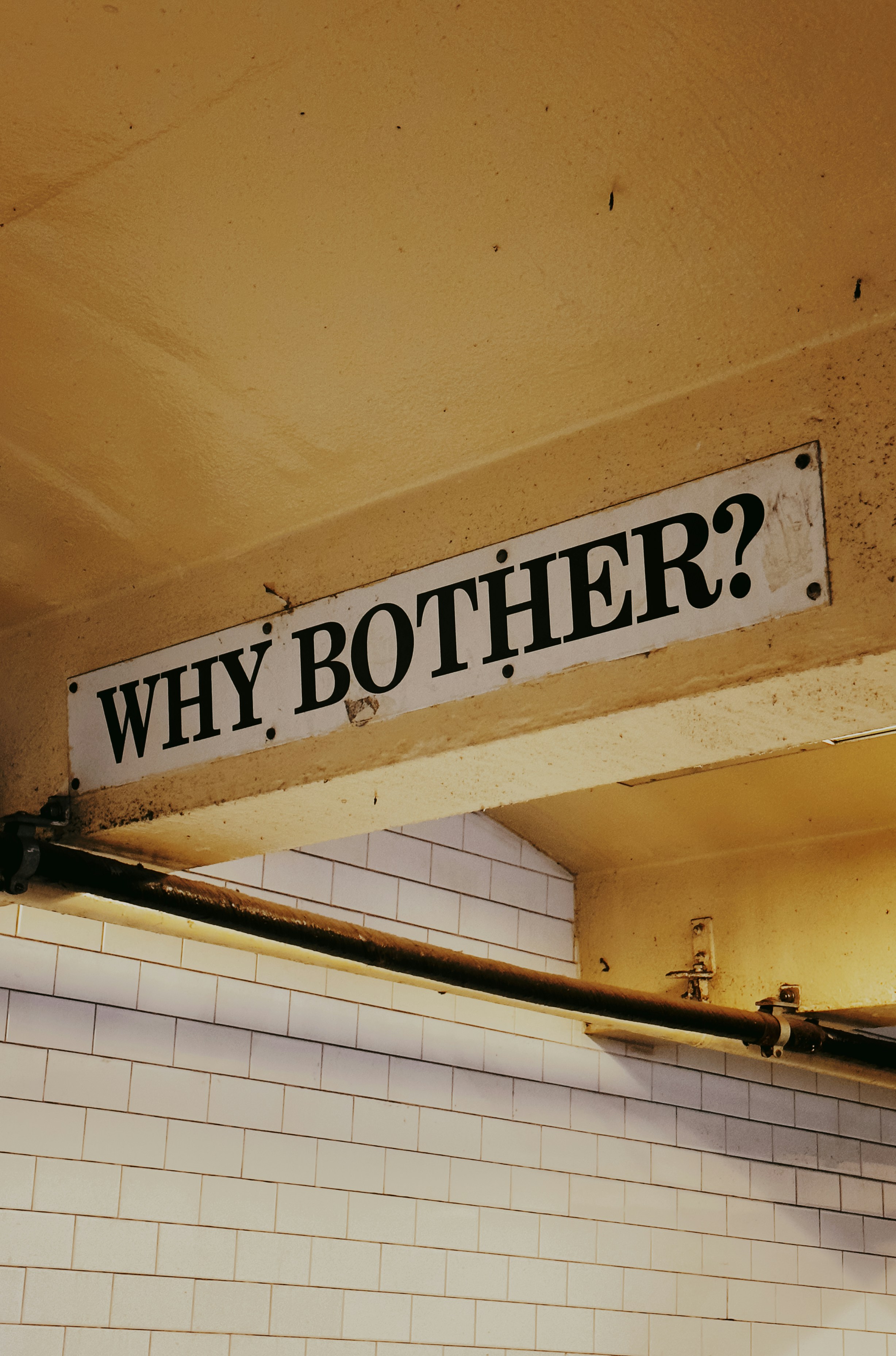 a sign that reads, why brother? above a tiled wall