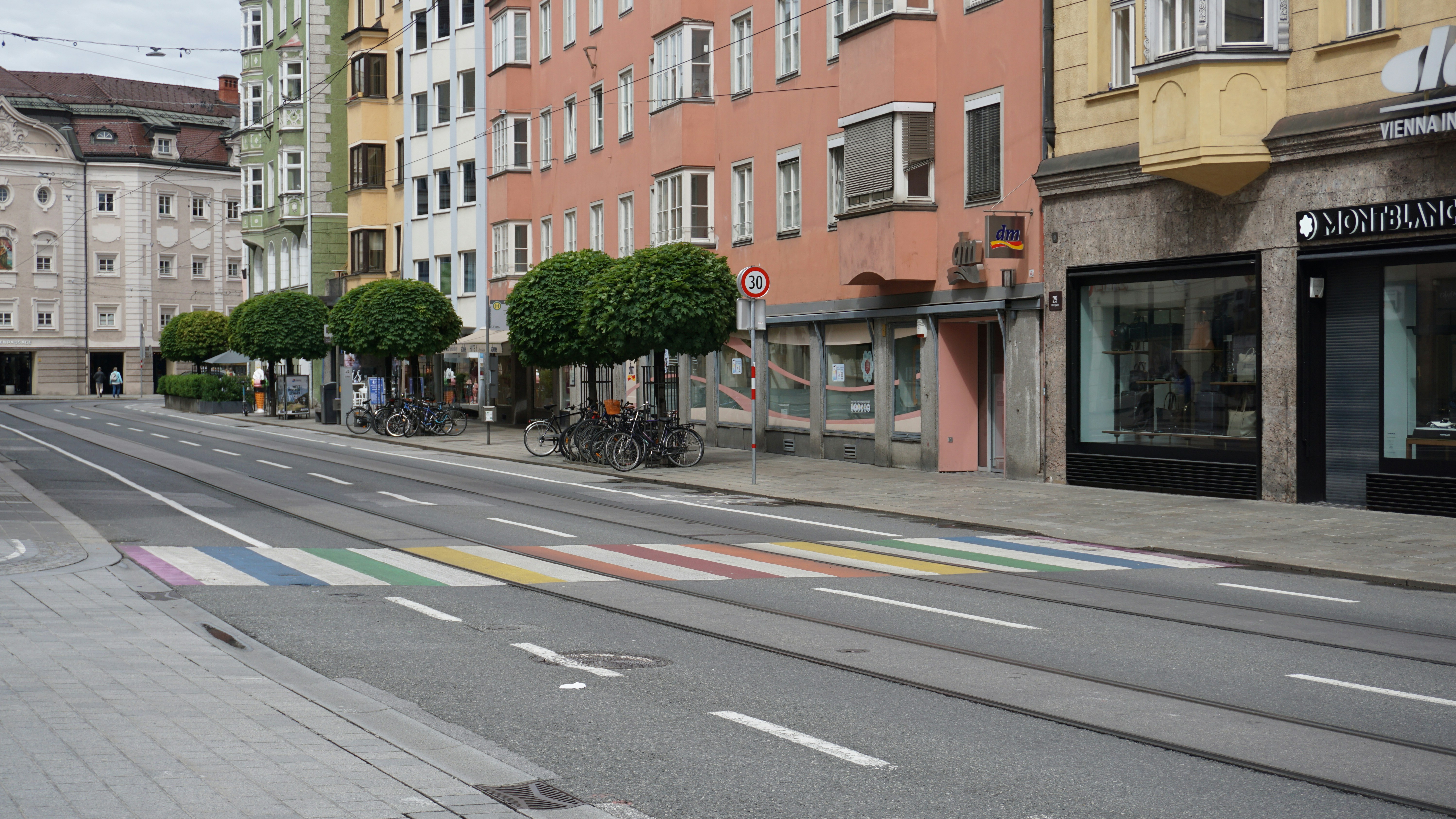 Lively street in Innsbruck city center with colorful buildings and bicycles parked along the sidewalk