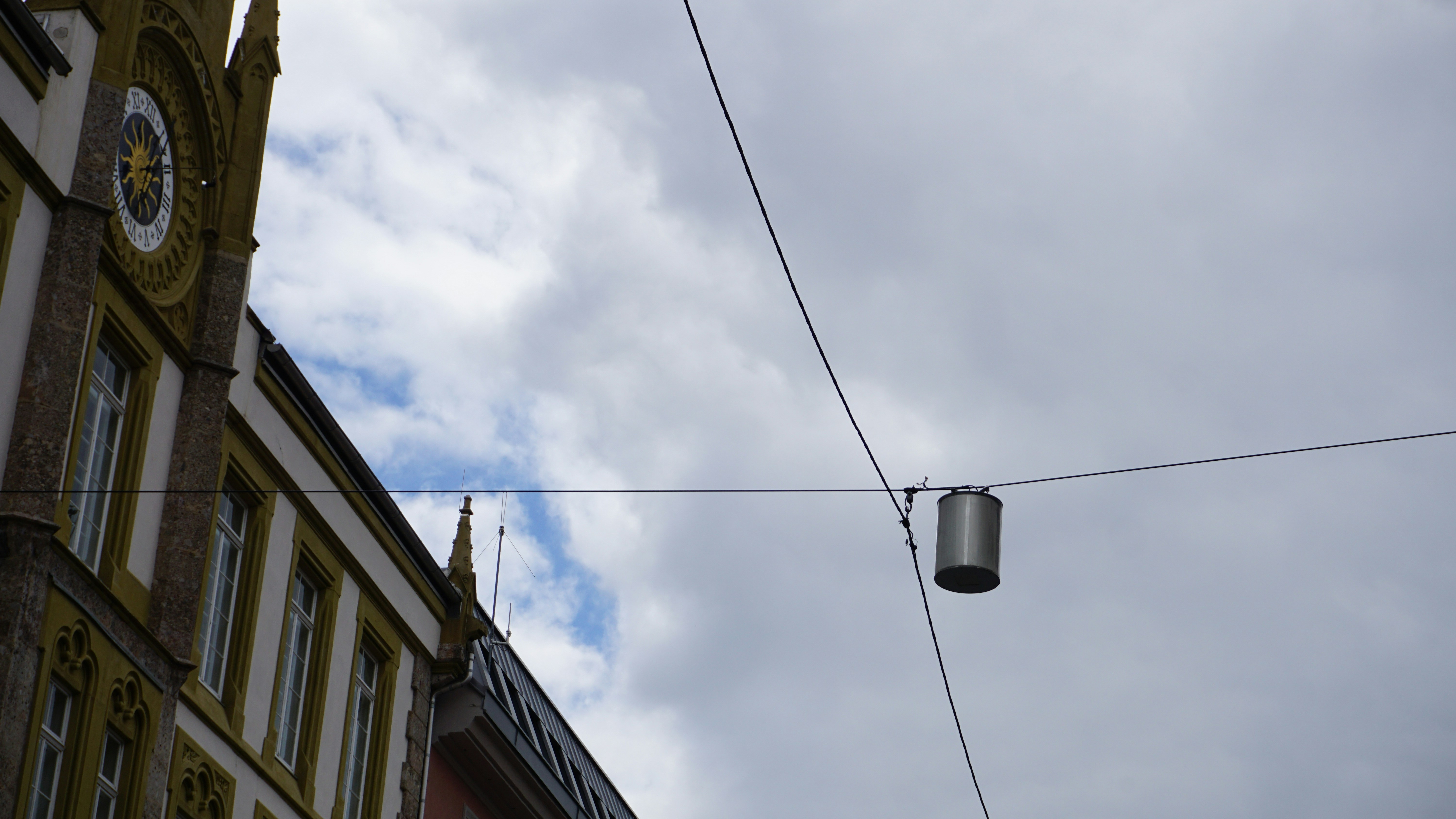 Una farola colgando de un cable al lado de un edificio