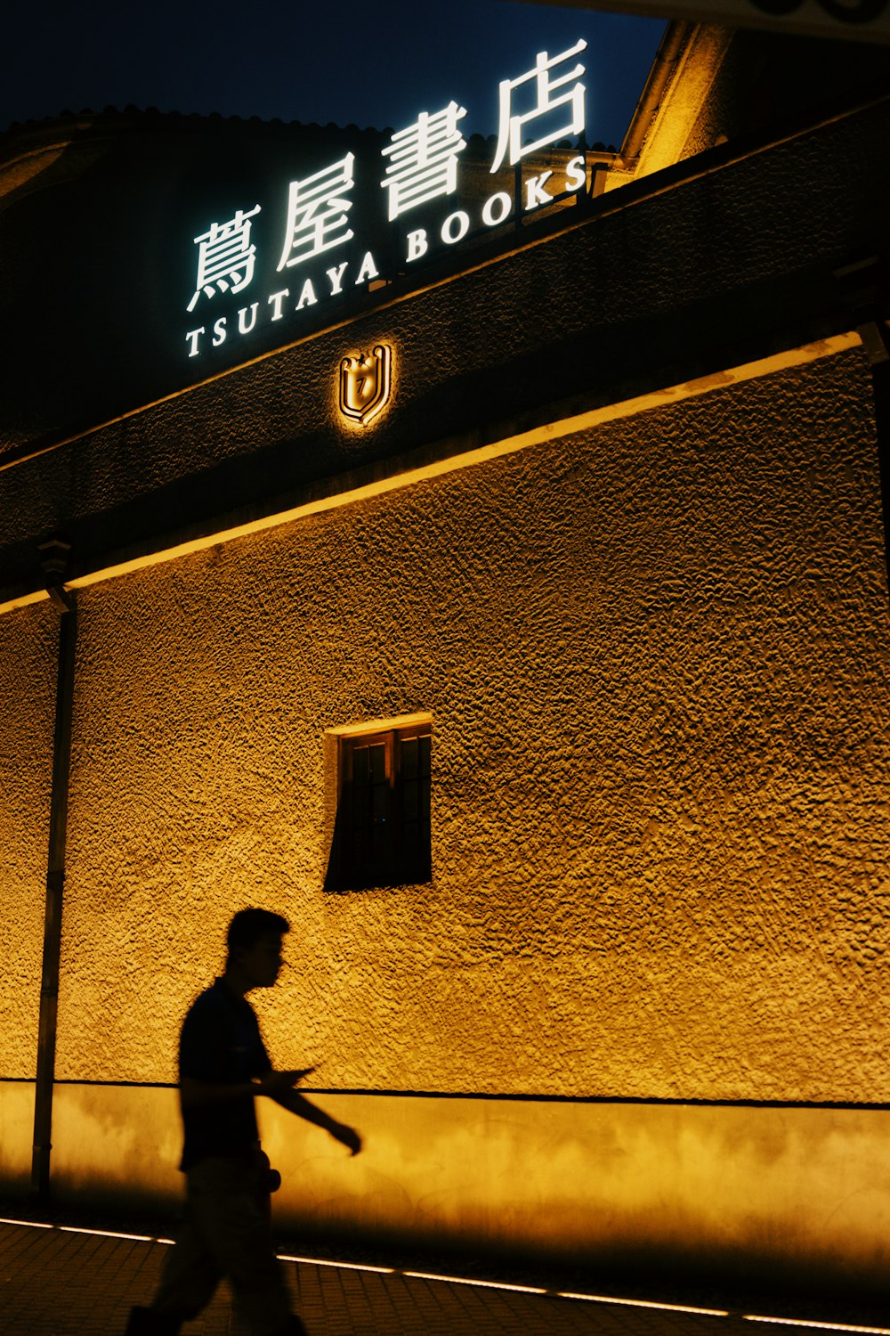 a man walking past a building at night