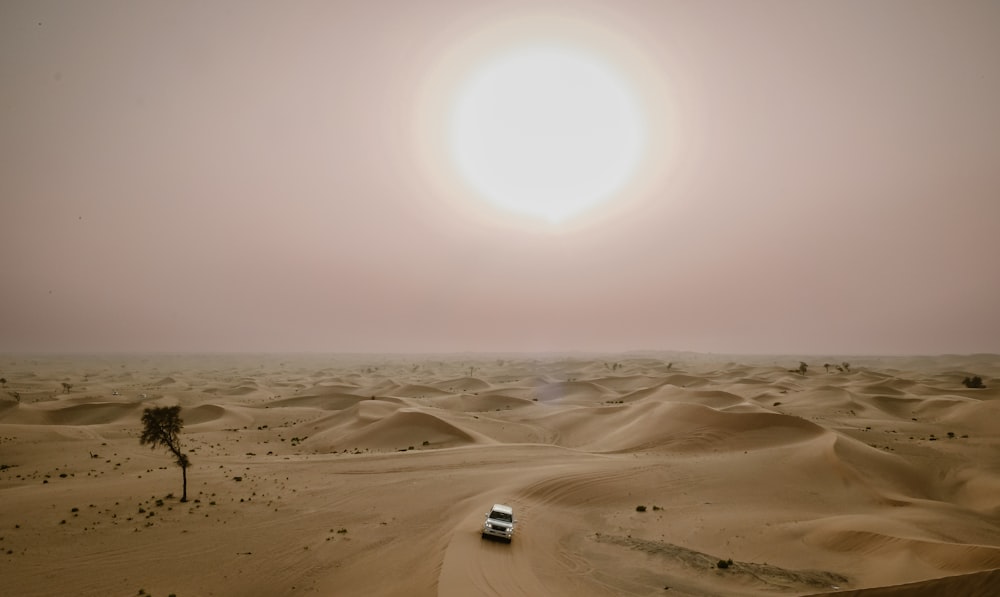 a car driving through the desert with the sun in the background