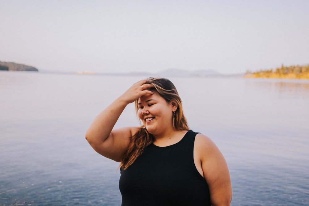 a woman in a black top is standing by the water