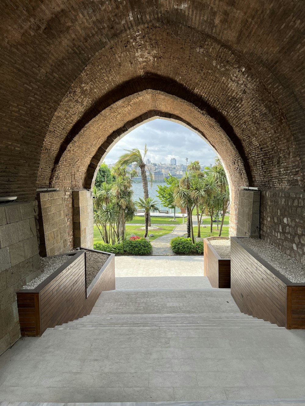 a stone tunnel with benches and palm trees
