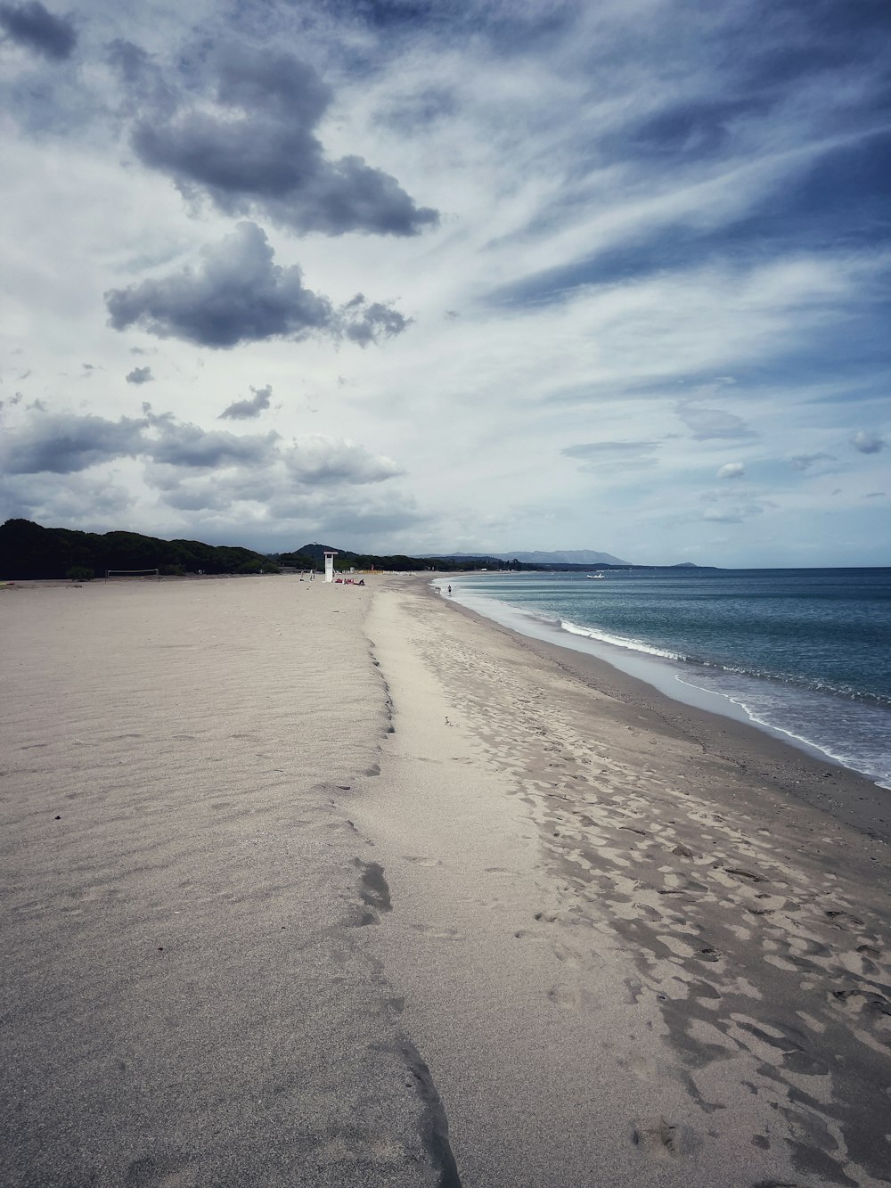 uma praia de areia ao lado do oceano sob um céu nublado