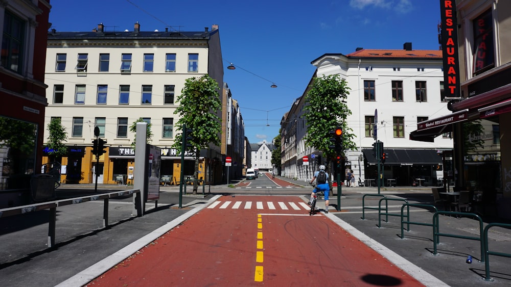 a man riding a bike down a street next to tall buildings