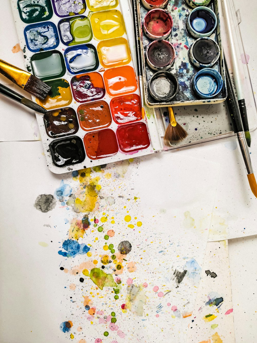 a palette of watercolors and a brush on a table