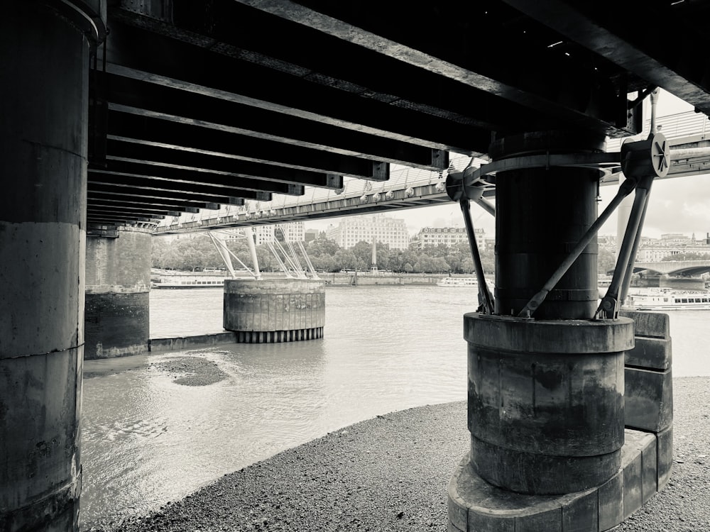 a black and white photo of a river under a bridge