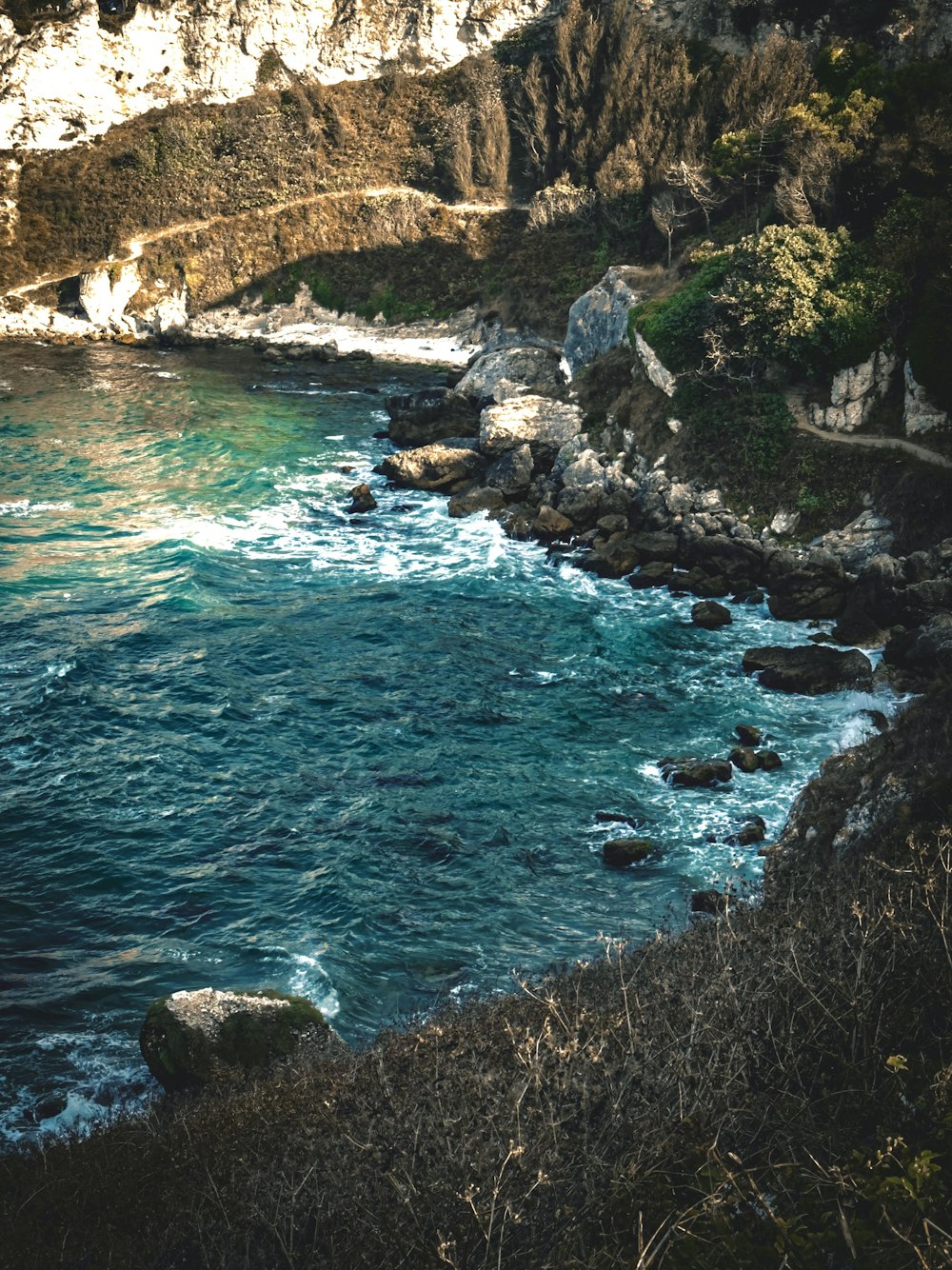 a large body of water next to a rocky cliff