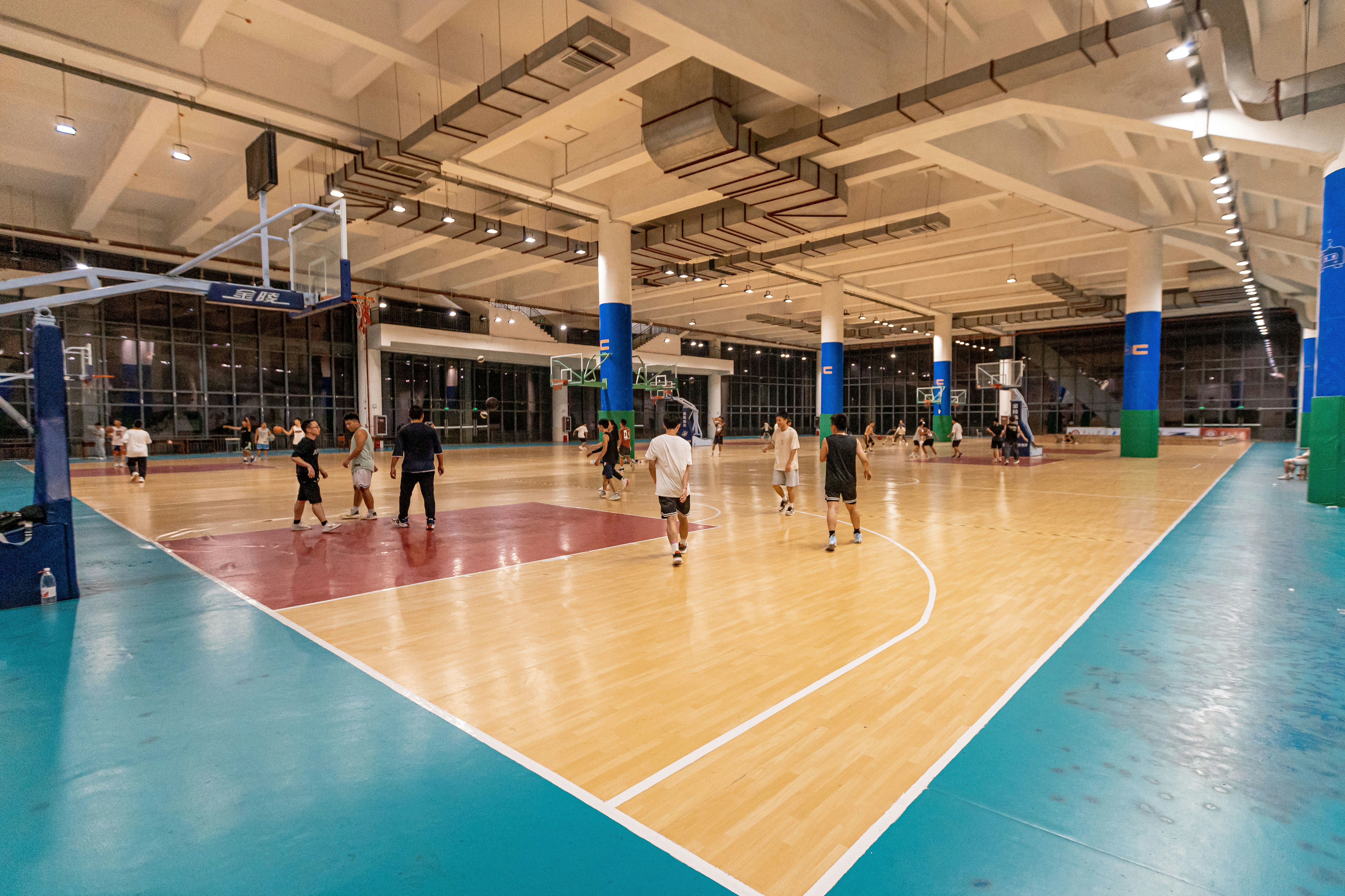 Indoor basketball court with polished hardwood floor and bright overhead lighting