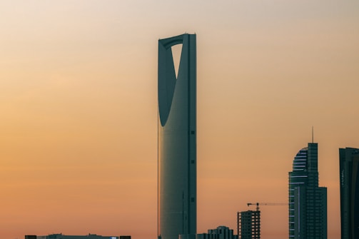 Modern luxury residential tower overlooking a vibrant city skyline at sunset.