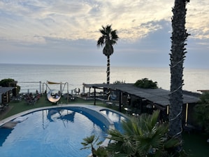 Guests enjoying the outdoor pool with a view of the Arabian Sea at sunset.