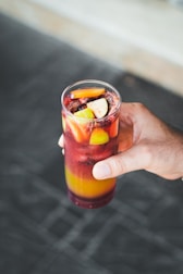 A colorful glass of freshly squeezed juice with ice and fruit garnishes.