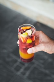 Colorful drink garnished with fresh fruits in a glass.