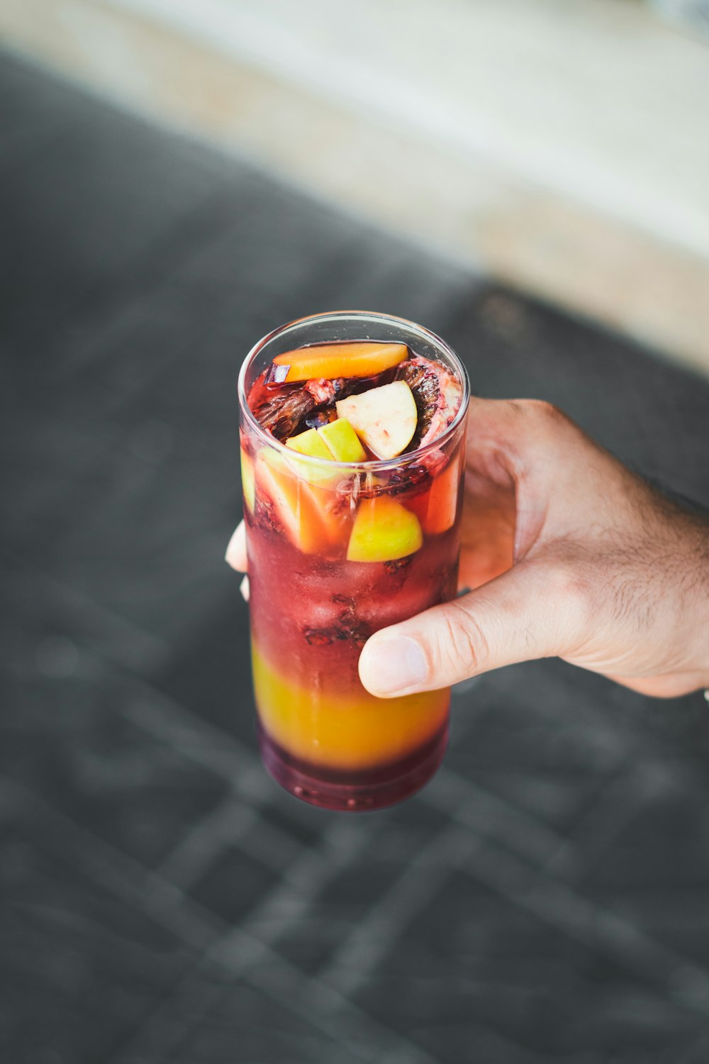a hand holding a drink with fruit in it