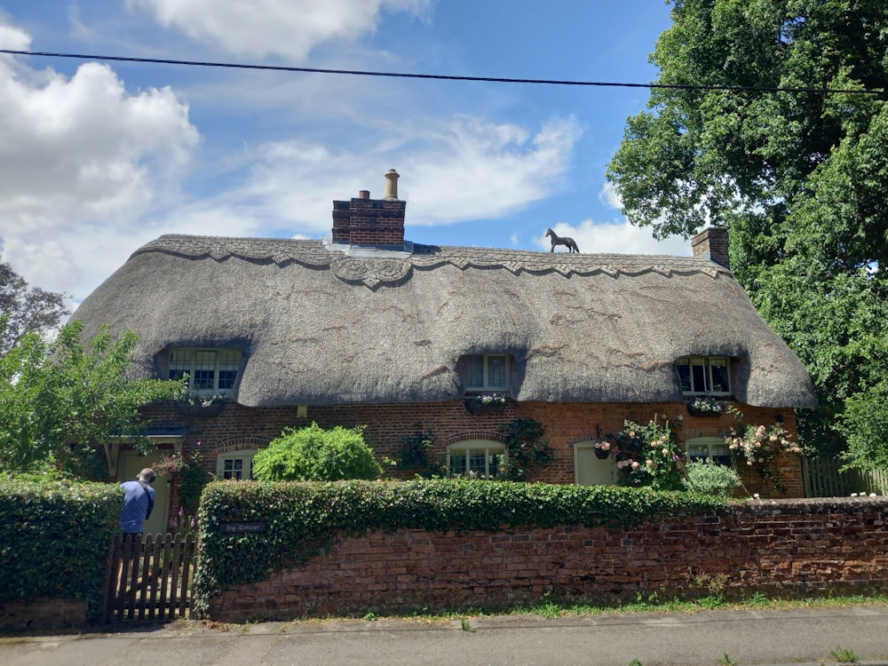 a man standing outside of a thatched roof house