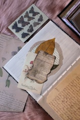 A flat lay of colorful vintage-style printable junk journal pages and ephemera scattered on a wooden table.