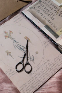 a pair of scissors sitting on top of a piece of paper