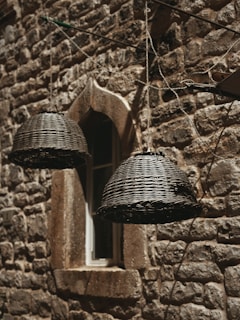 Close-up of a woven seagrass wall basket hanging on a textured white wall, sunlight casting soft shadows.