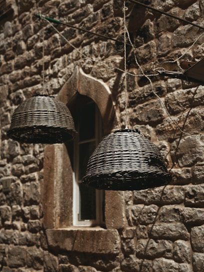 Close-up of a woven seagrass wall basket hanging on a textured white wall, sunlight casting soft shadows.