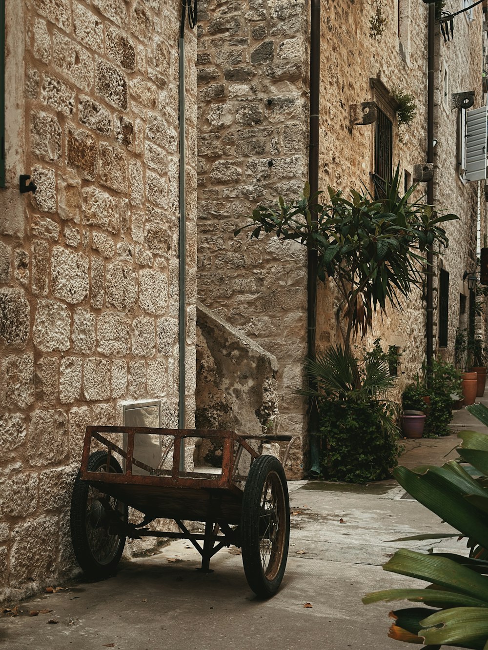 an old wooden cart parked in front of a stone building