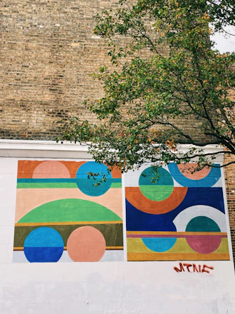 A colorful mural being printed directly onto a textured brick wall outdoors.