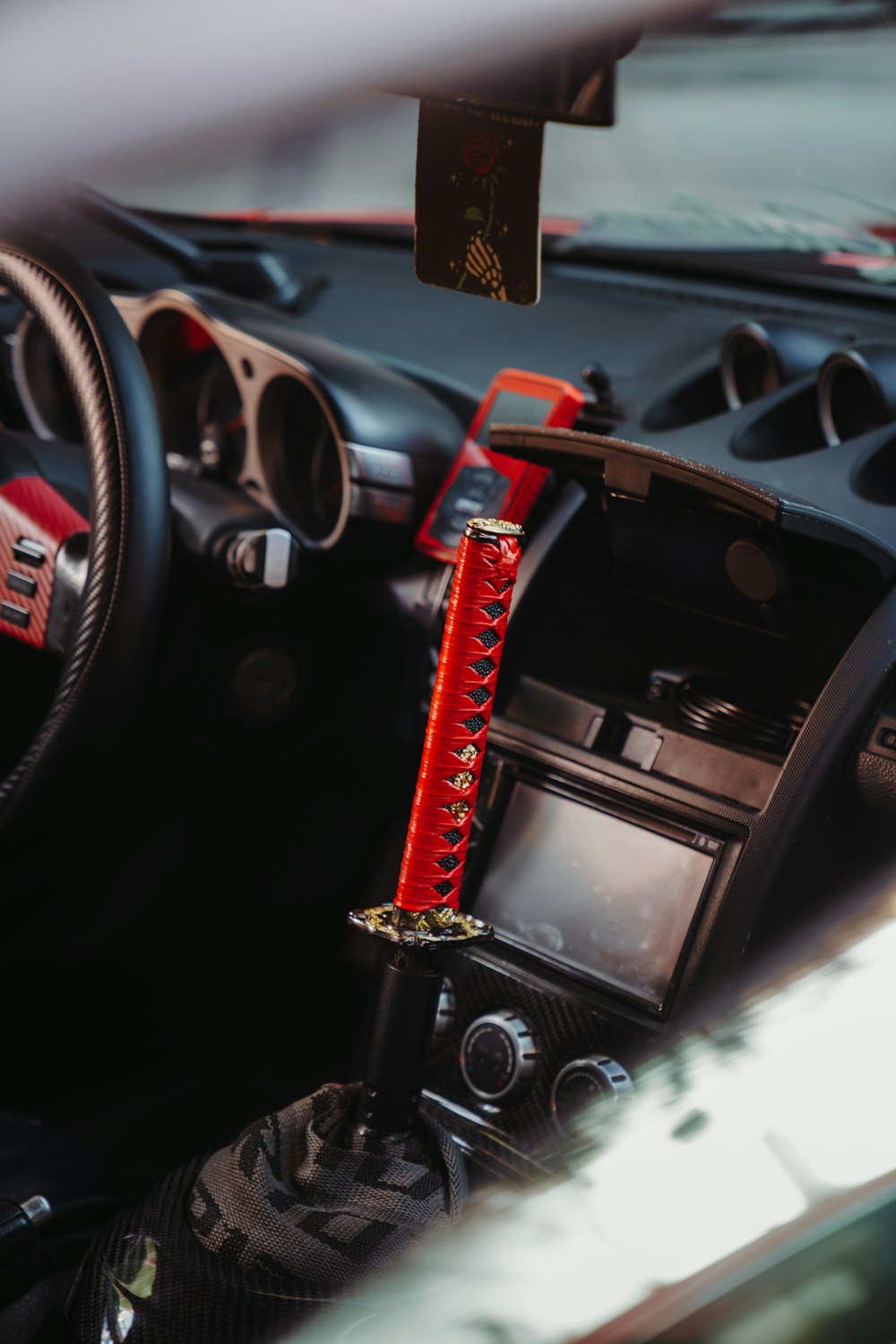 a car dashboard with a steering wheel and a red stick sticking out of it