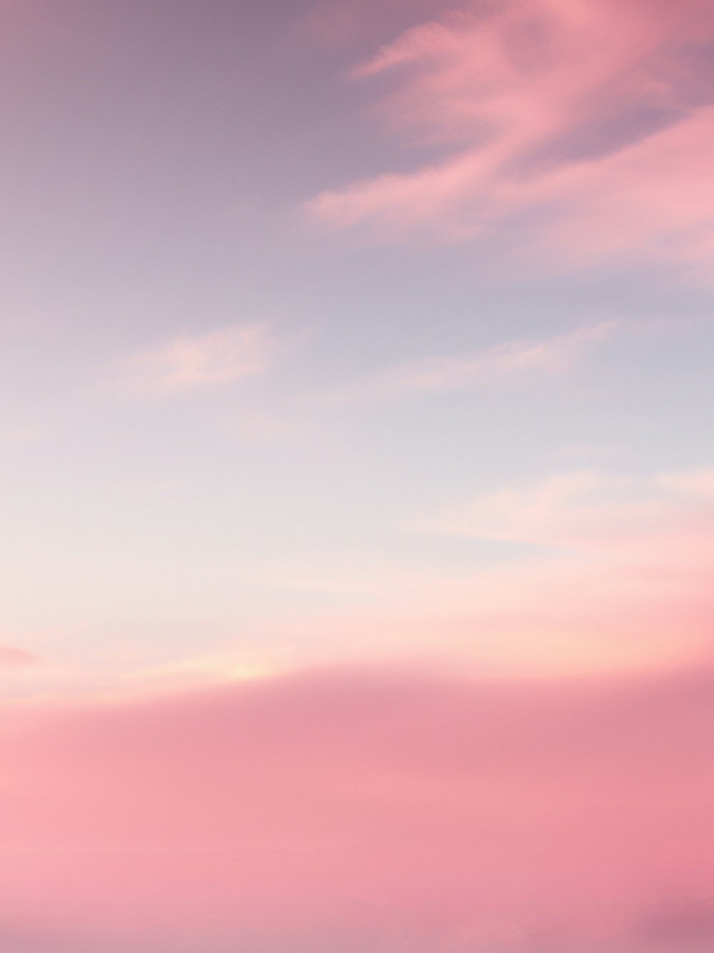 a plane flying in the air with a pink sky in the background