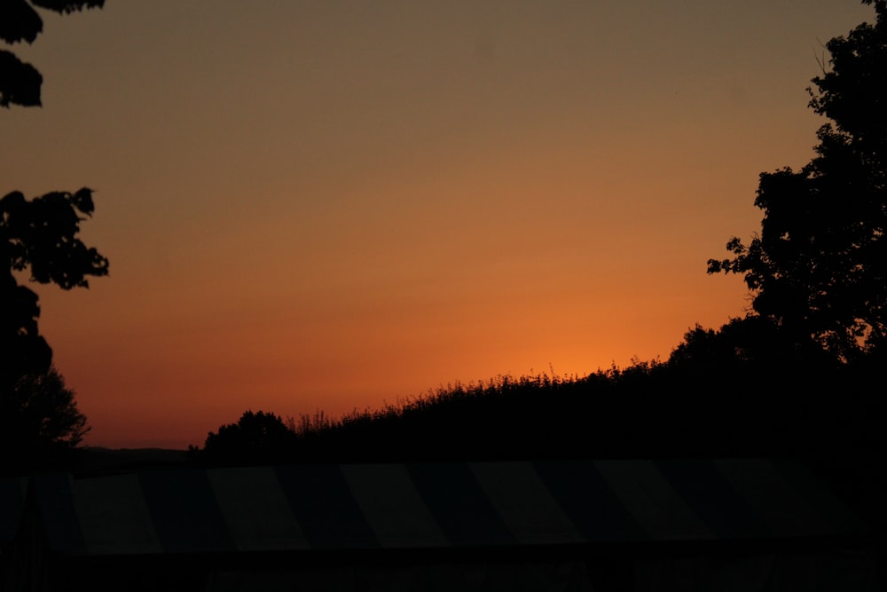 o sol está se pondo sobre uma colina com árvores