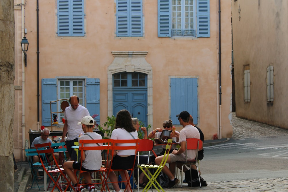 a group of people sitting around a table in front of a building