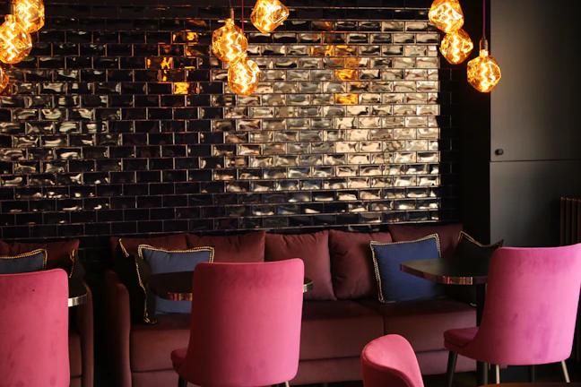 Interior shot of the lounge showcasing deep burgundy seating, black walls, and soft golden glow.