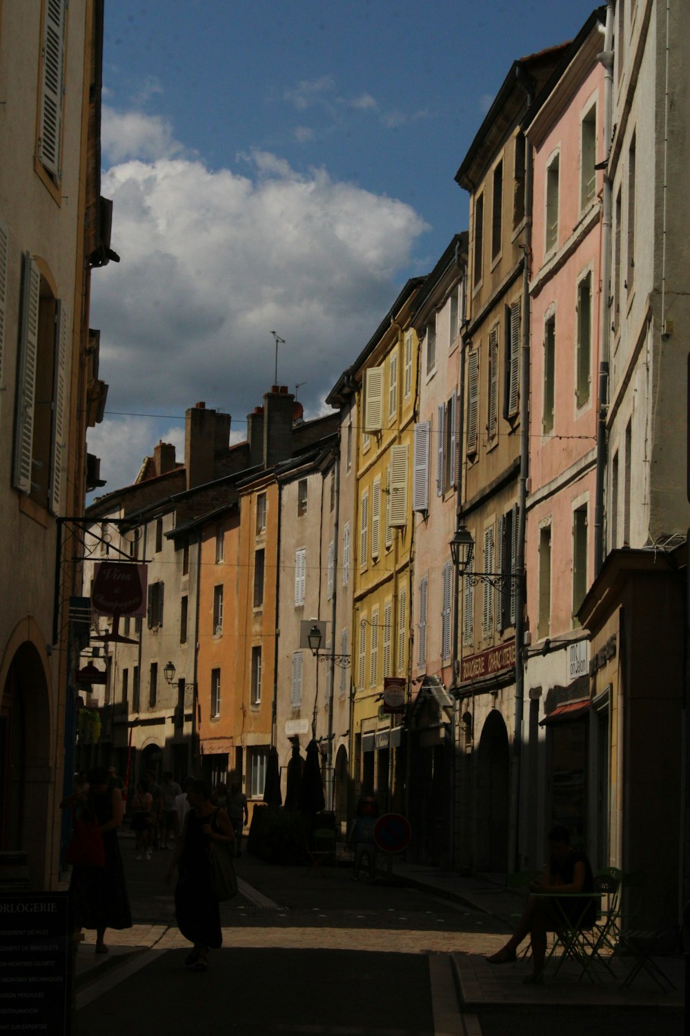 a woman walking down a street next to tall buildings