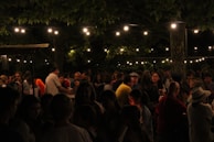 Crowd enjoying an outdoor bar area under string lights at night.