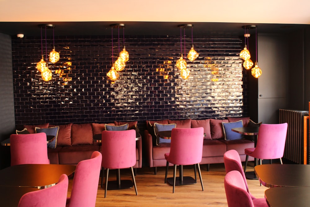 a restaurant with pink chairs and a black wall