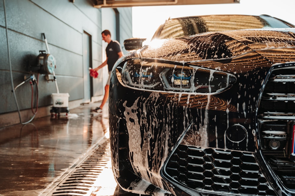 a man washing a sports car in a garage