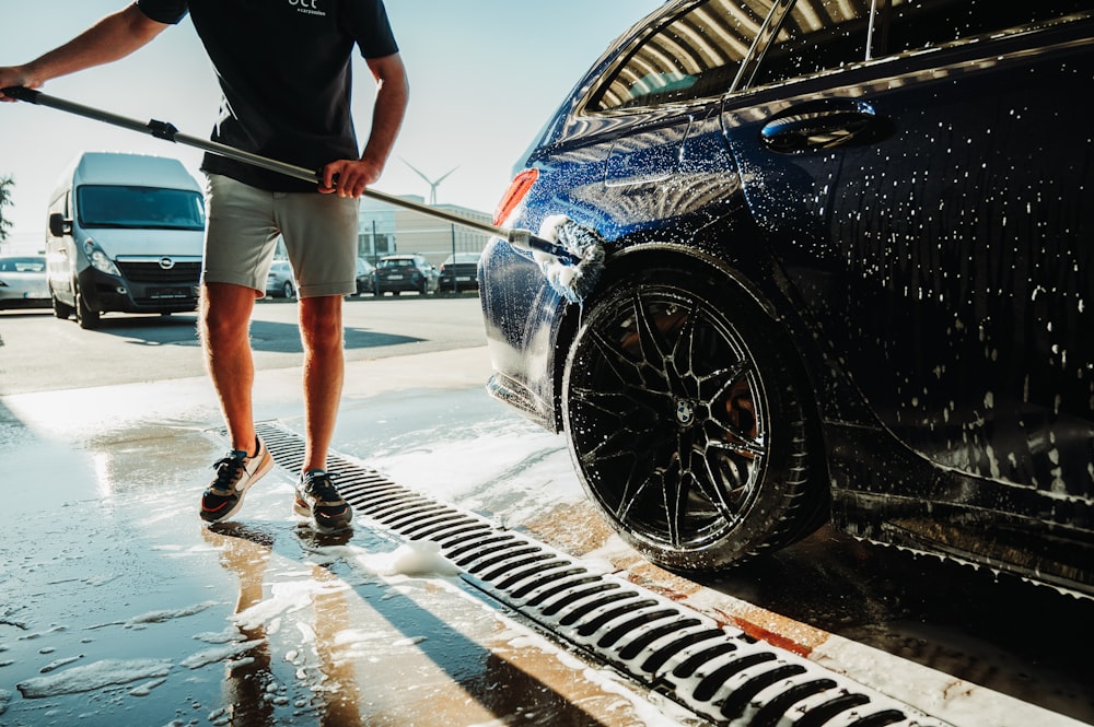 a man is washing a car with a hose