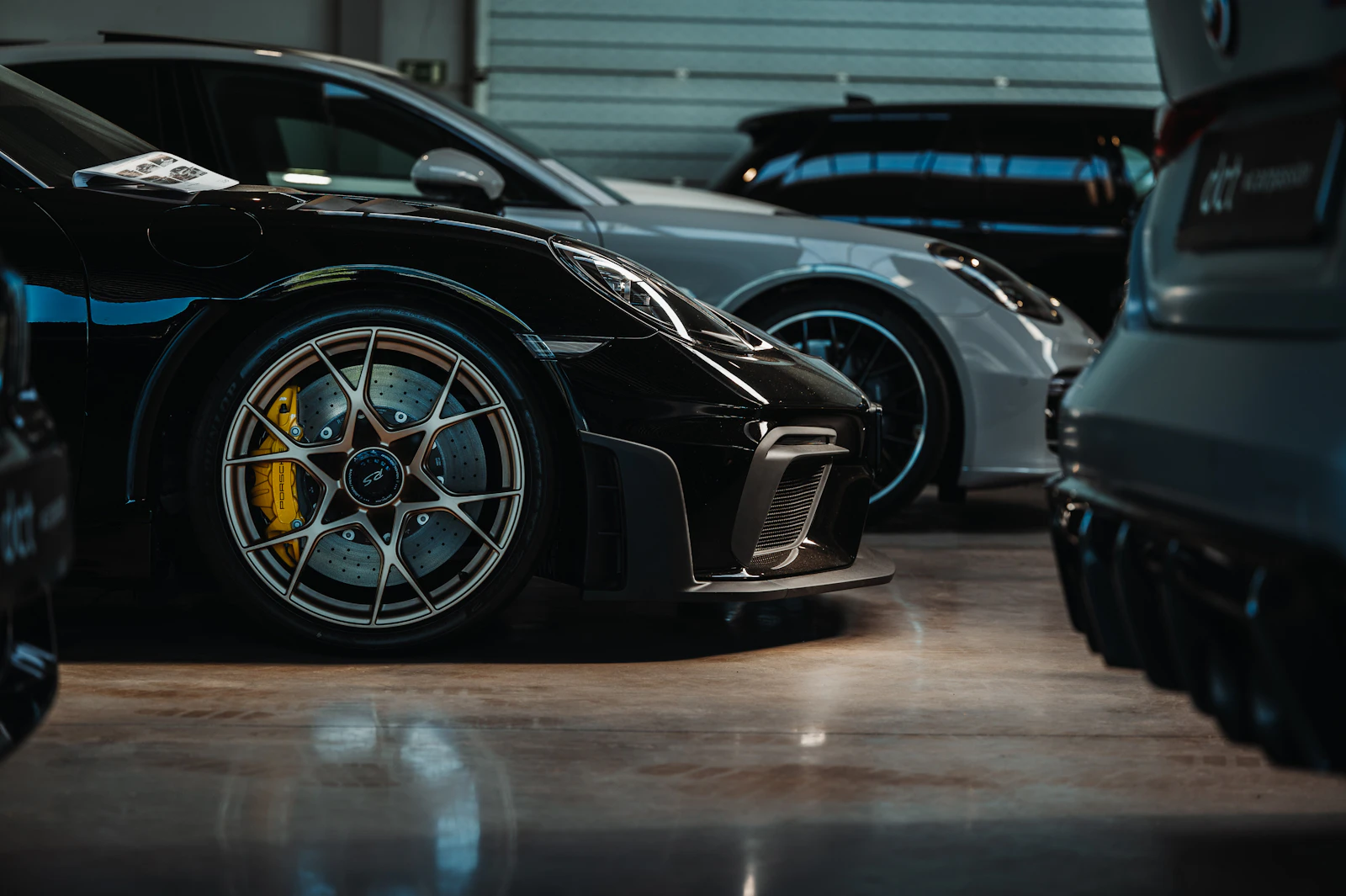 Black Porsche 911 GT3 with yellow brake calipers in a dark garage