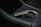 A luxurious car key fob rests in a car's cup holder, showing intricate design details and a logo. The setting includes sleek black leather with white stitching and a metallic interior accent.