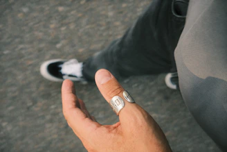 Close-up of a hand wearing layered minimalist silver rings against a soft urban backdrop.