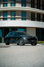 A sleek luxury car parked outside a modern office building.