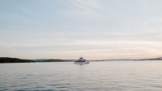 A serene view of a yacht anchored in a calm bay at sunset.