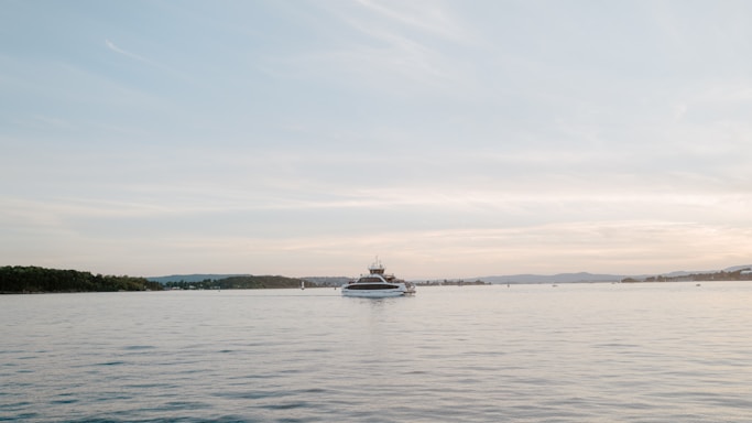 A serene view of a yacht anchored in a calm bay at sunset.