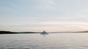 A serene sunset over a calm ocean with a luxury yacht in the distance.