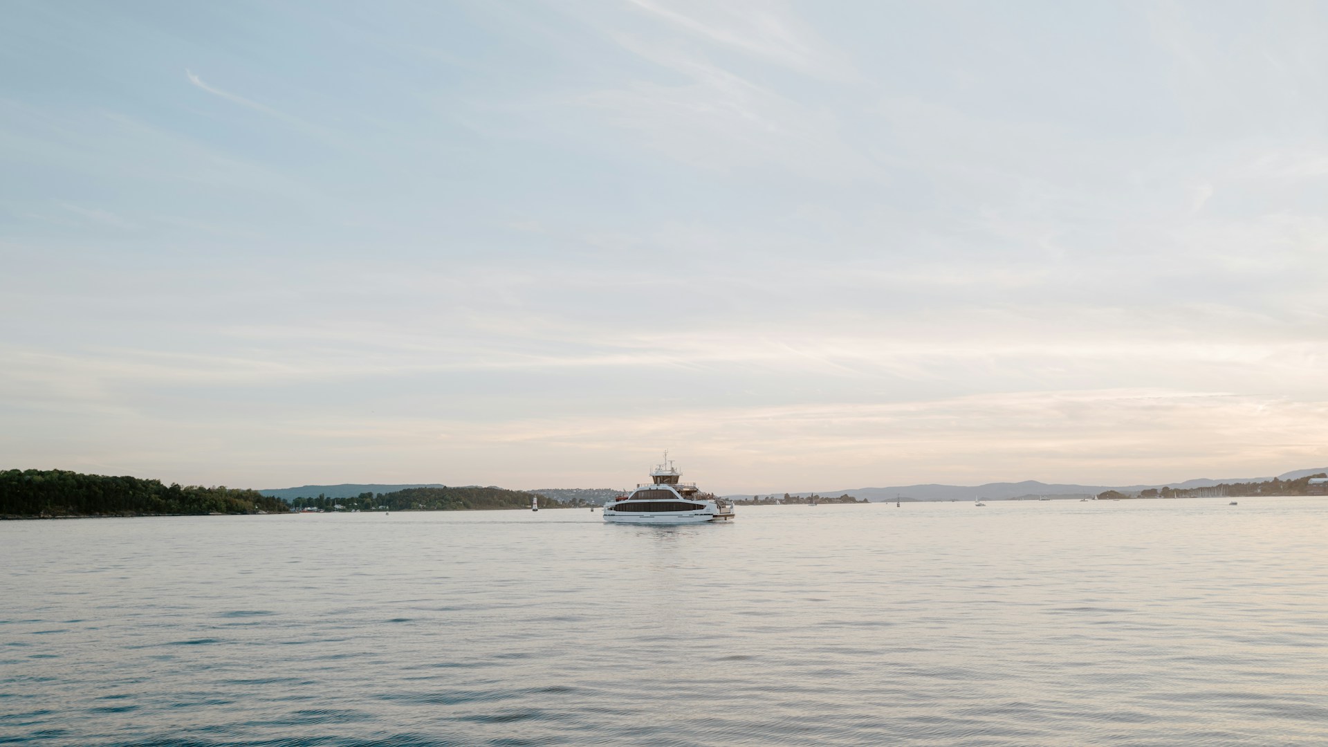 A panoramic view from the yacht’s upper deck capturing the serene sea, distant islands, and a sky transitioning from warm sunset tones to a deep, regal night.